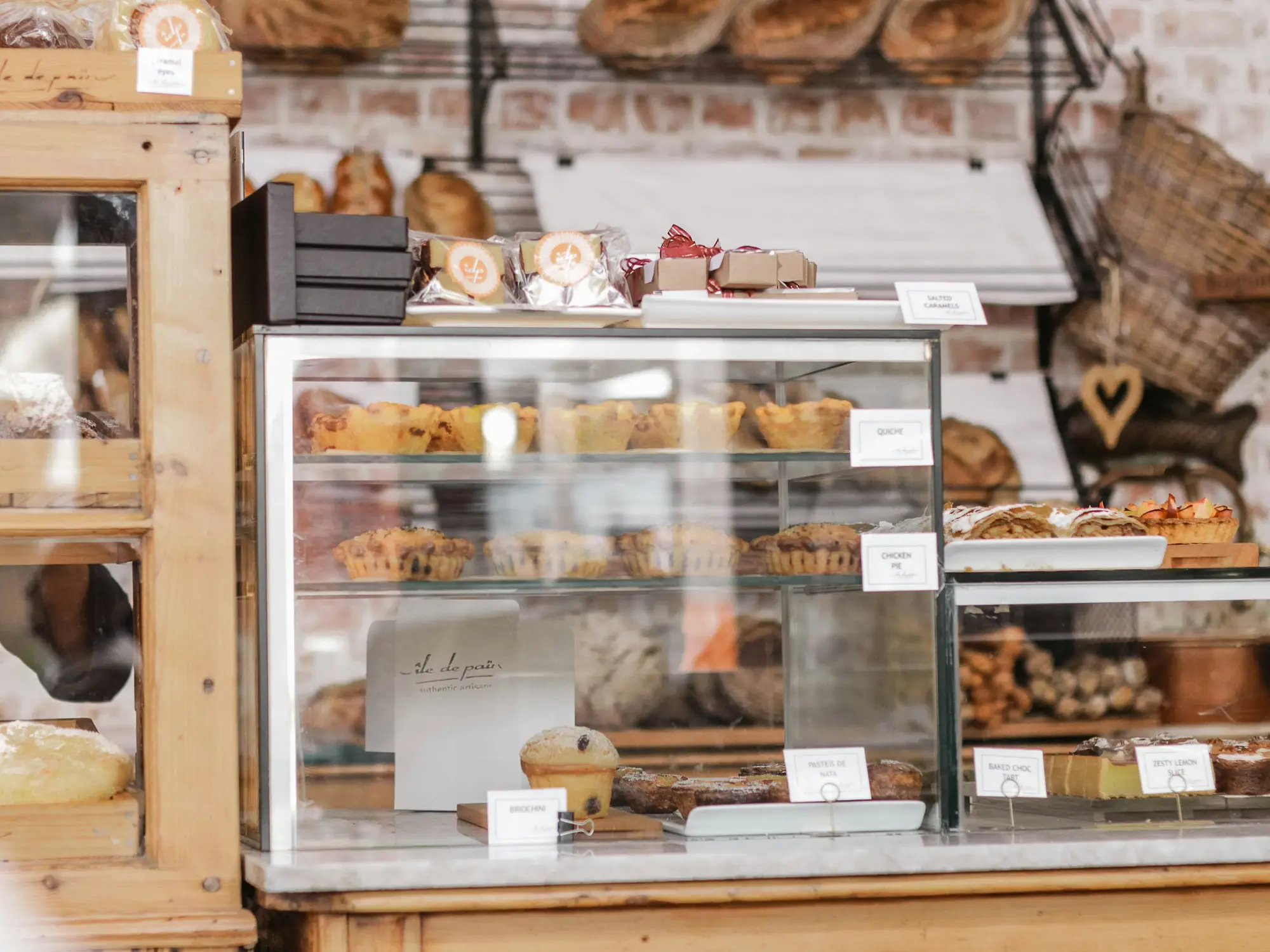 Bakery display counter with pies and tarts under glass and wrapped gift boxes stacked on top, ready for pre-order pickups
